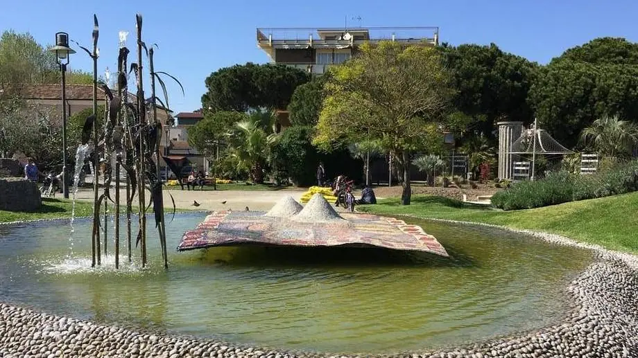 The Il Tappeto Sospeso basin in Piazzale dei Salinari, with metal reeds spraying water and trees in the background