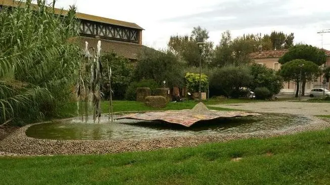 Il Tappeto Sospeso in its lawn-surrounded basin, with reeds and Magazzino del Sale in the left background