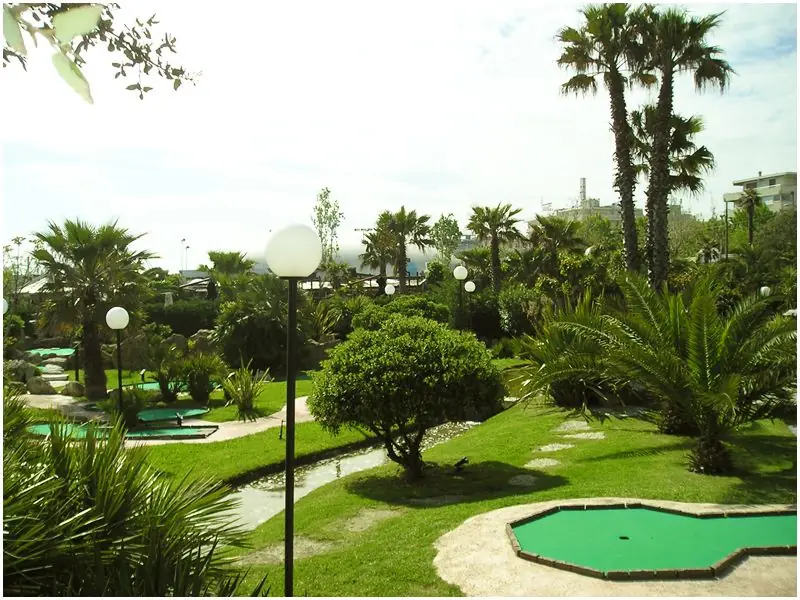 Les pistes du Rivergreen Golf entre palmiers, haies et petit ruisseau, avec des lampadaires à globe sur la pelouse