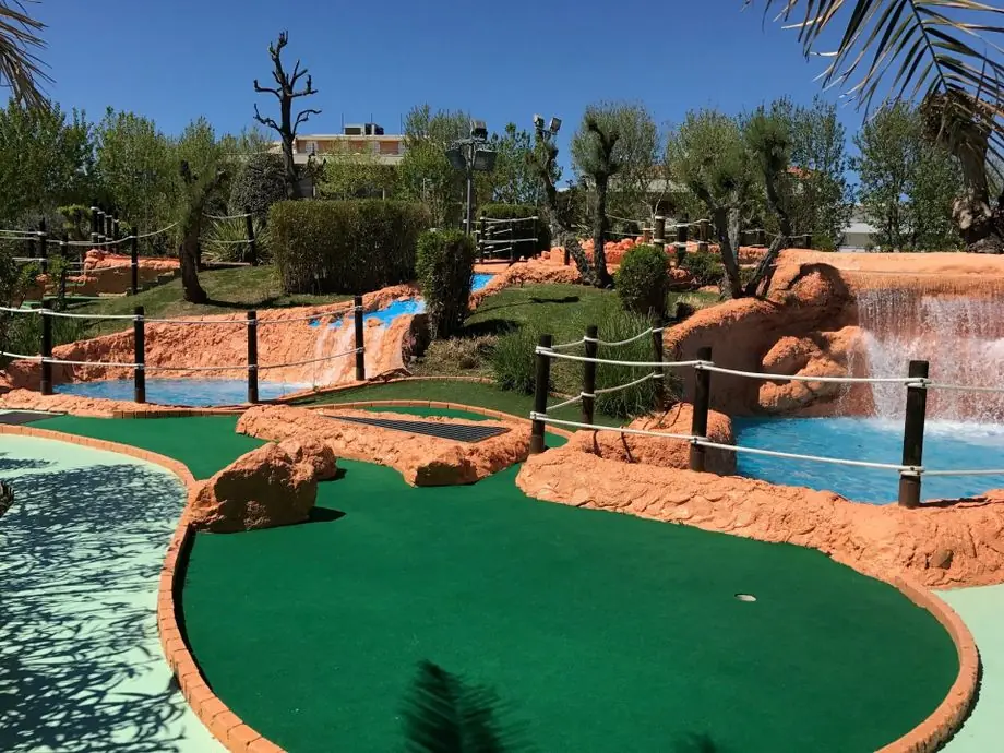 Une piste verte d'Indiana Golf parmi des rochers orange, des cascades et des clôtures de corde, par une journée ensoleillée