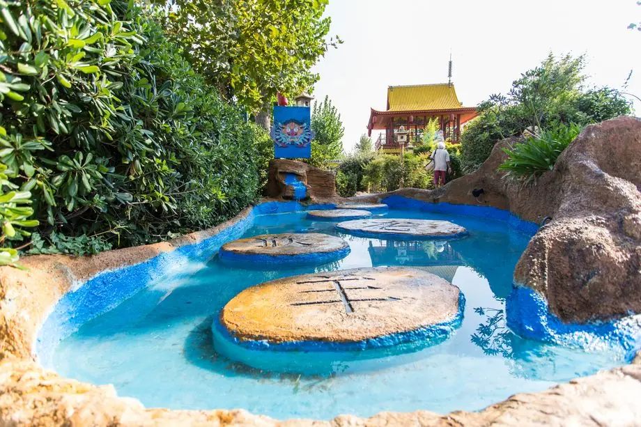 A blue water ride among artificial rocks and vegetation at Fiabilandia