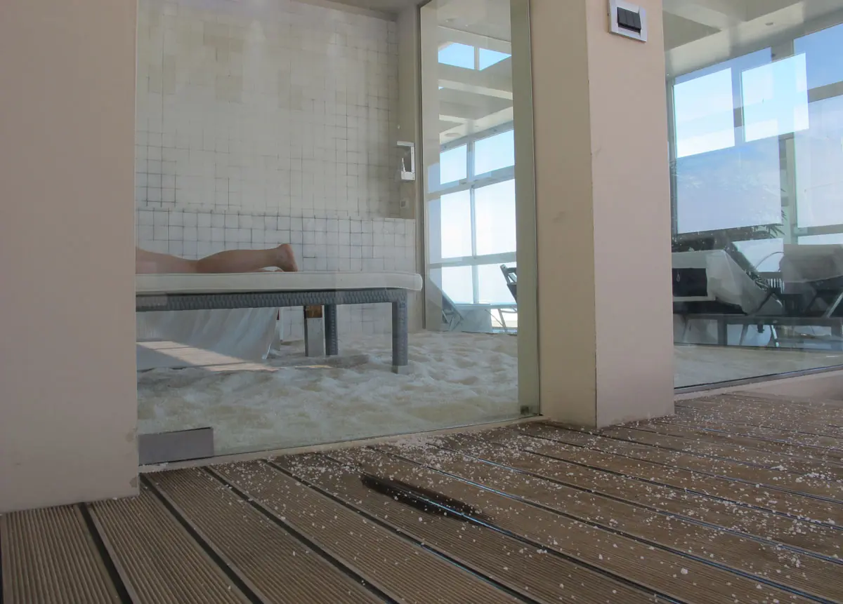 La stanza del sale di Rimini Terme, con il pavimento coperto di sale grosso, un lettino e le vetrate luminose sullo sfondo