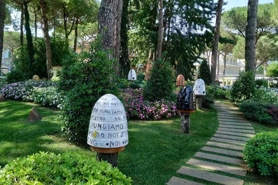 Un'aiuola fiorita di una rotonda con arnie decorative dipinte, fra i pini di Milano Marittima