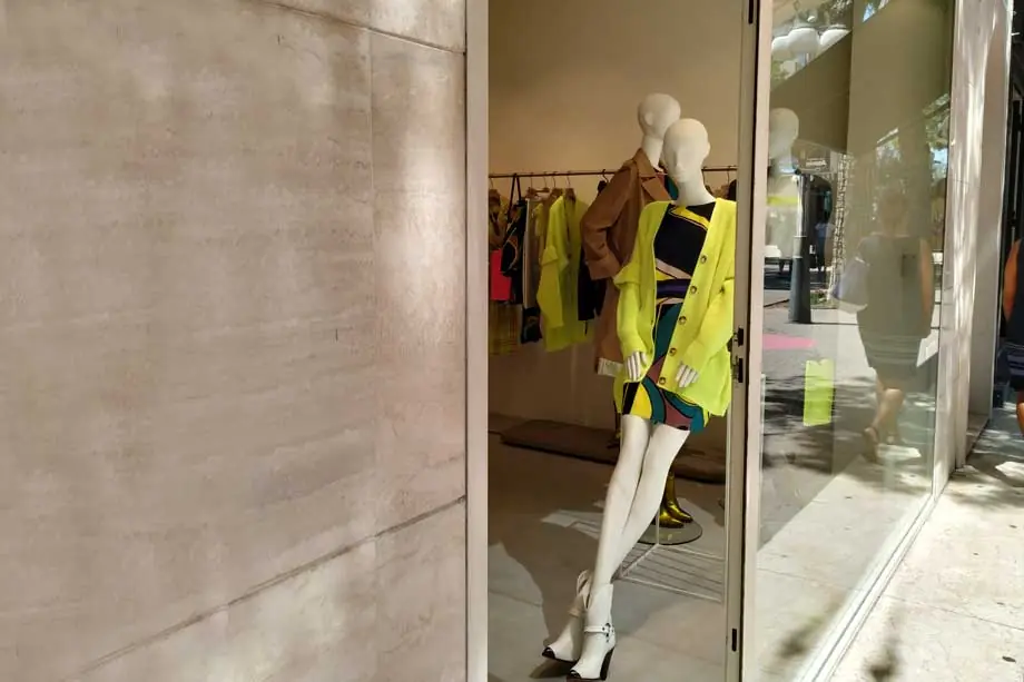 Ein Schaufenster mit Schaufensterpuppen am Viale Ceccarini in Riccione neben einer mit hellem Stein verkleideten Wand