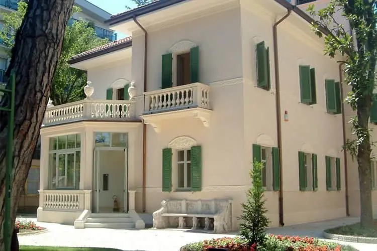 La Villa Franceschi à Riccione, villa de style Liberty avec balcon en pierre et volets verts, vue du jardin