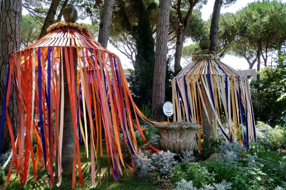 Ein Beet an der Rotonda Cadorna mit Vorhängen aus bunten Bändern zwischen den Pinien von Milano Marittima