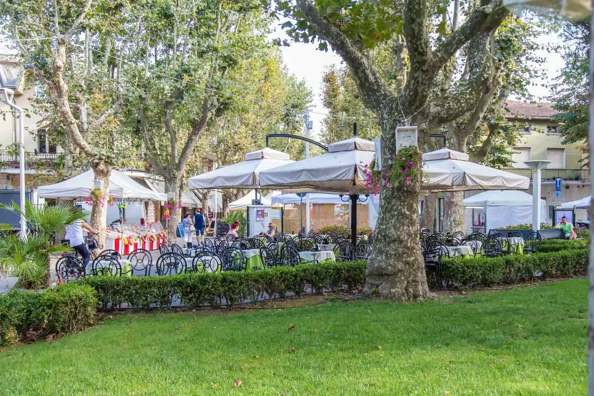 Tables in the shade of plane trees on Isola dei Platani in Bellaria, a tree-lined pedestrian street