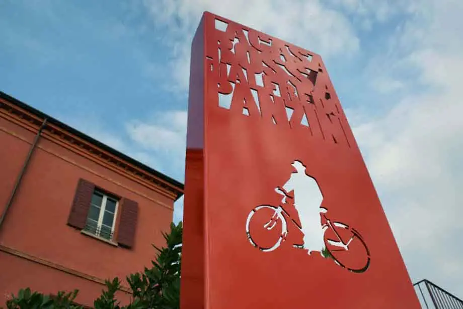 The red sign with the museum's name and a silhouette of a man on a bicycle, in front of Casa Rossa's façade
