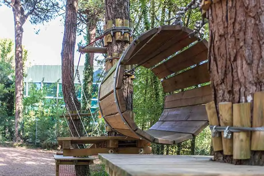 A tunnel of wooden slats suspended among the pines, one of the crossings at CerviAvventura in Cervia's pinewood
