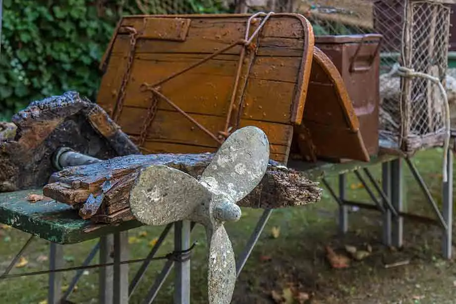 A propeller, a wooden boat rudder and a wire cage, fishing equipment displayed in the Torre Saracena garden