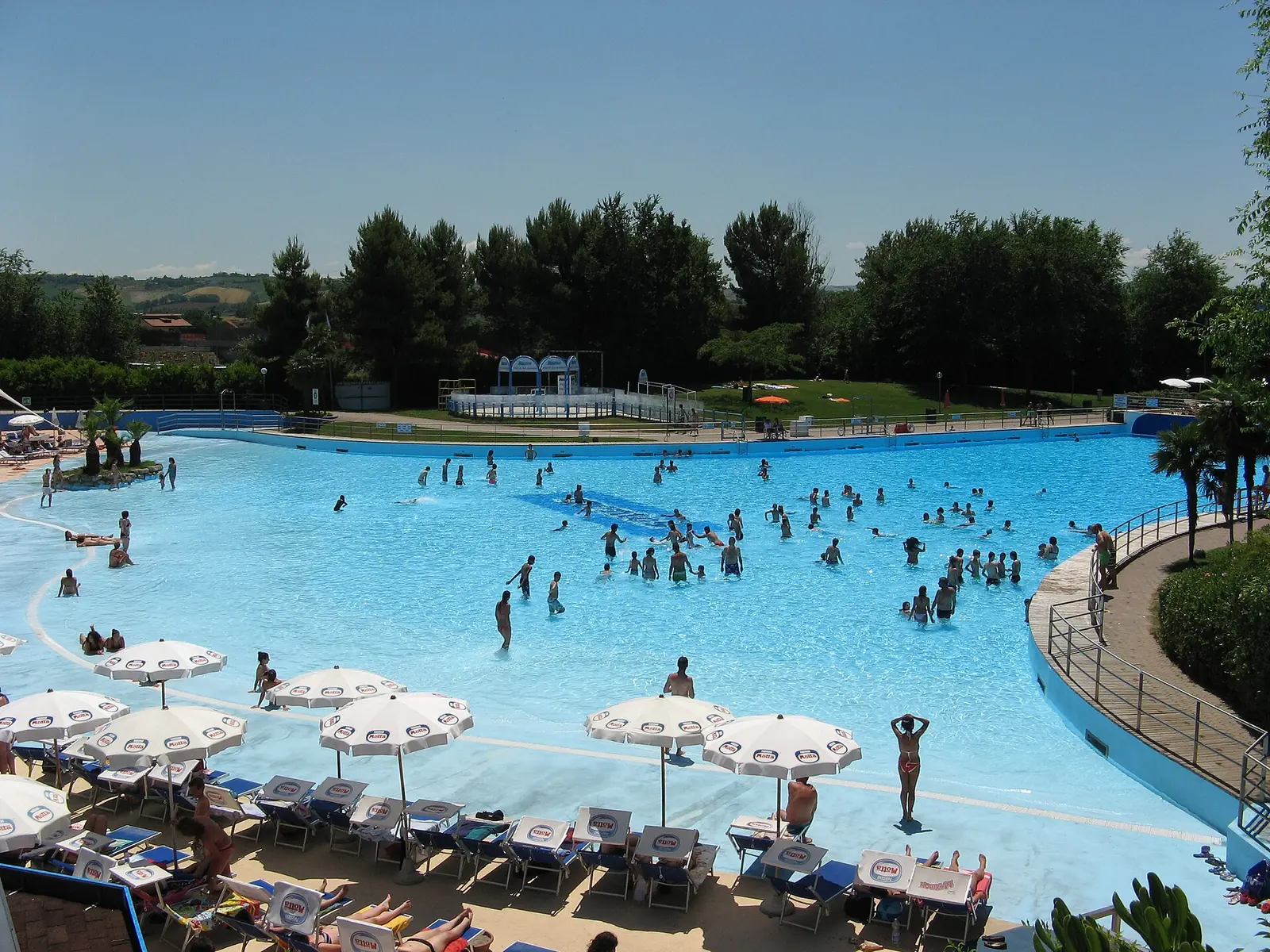 Das große Wellenbecken des Aquafan in Riccione von oben mit Badegästen im Wasser und Hügeln im Hintergrund