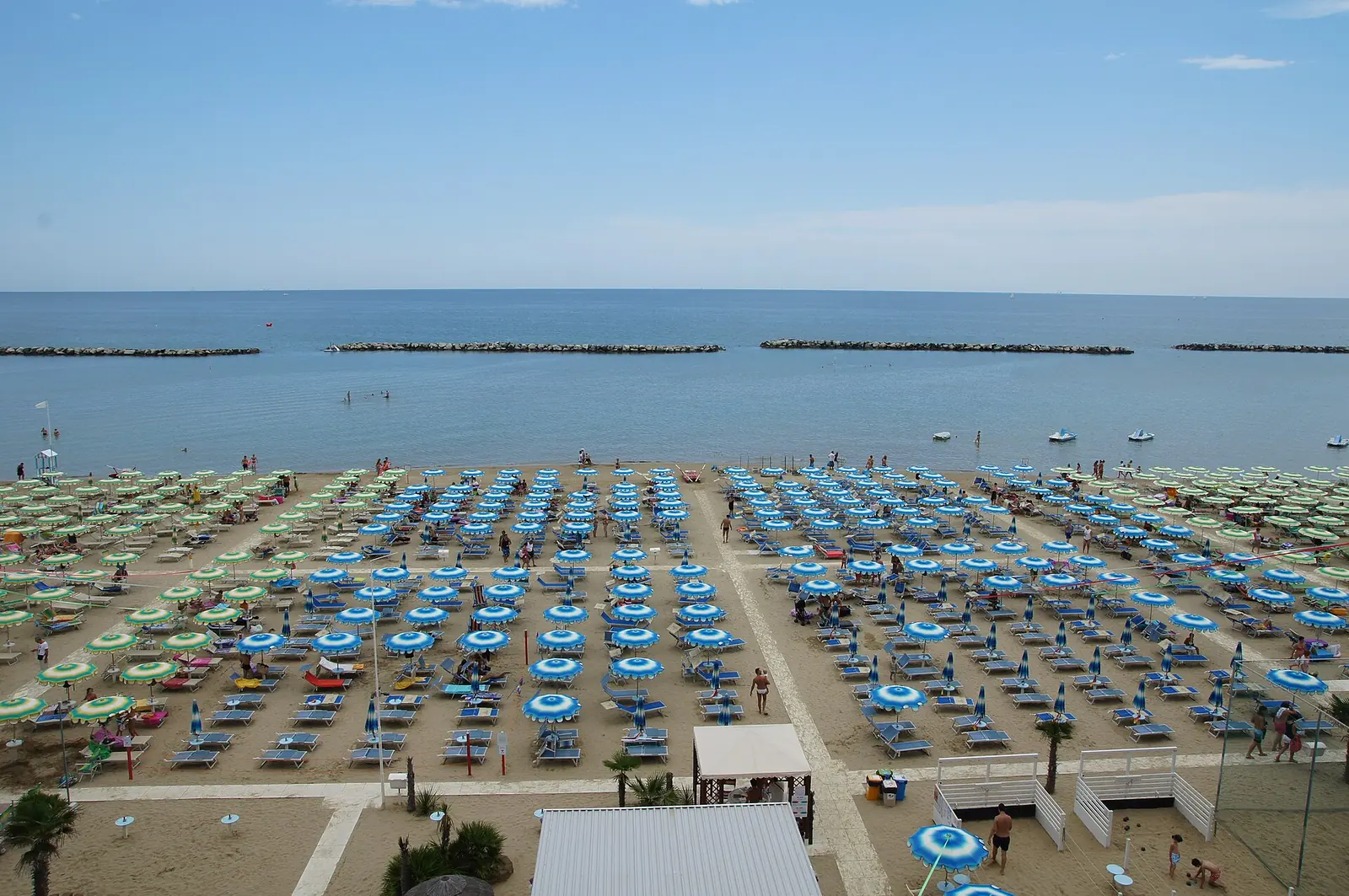 La spiaggia di Igea Marina vista dall'alto, con le file di ombrelloni blu e verdi e le scogliere frangiflutti davanti al mare