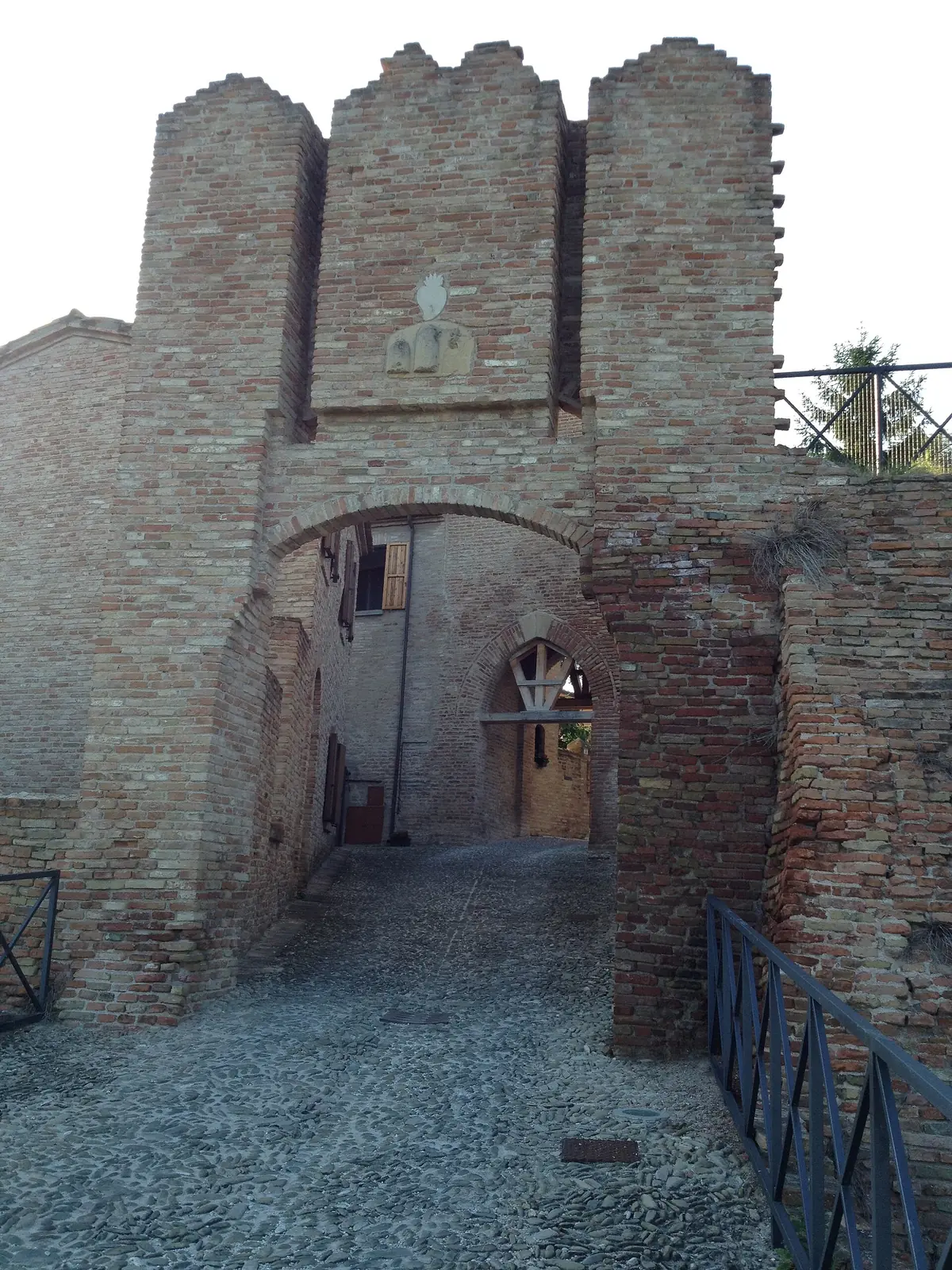 La porta del Castello di Coriano, con la torre merlata e lo stemma murato sopra l'arco