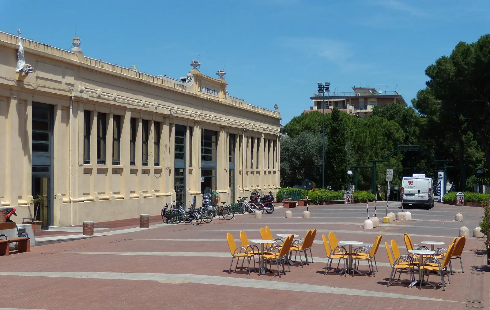 Il Mercato Coperto di Cattolica con la facciata gialla, le biciclette e i tavolini all'aperto sulla piazza