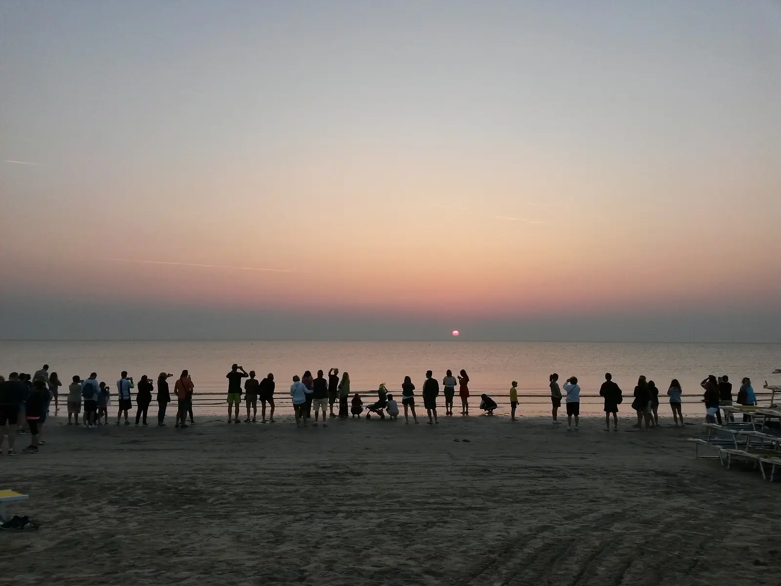 Silhouetten von Menschen am Strand von Pinarella bei Sonnenaufgang mit Blick auf die über dem Meer aufgehende Sonne