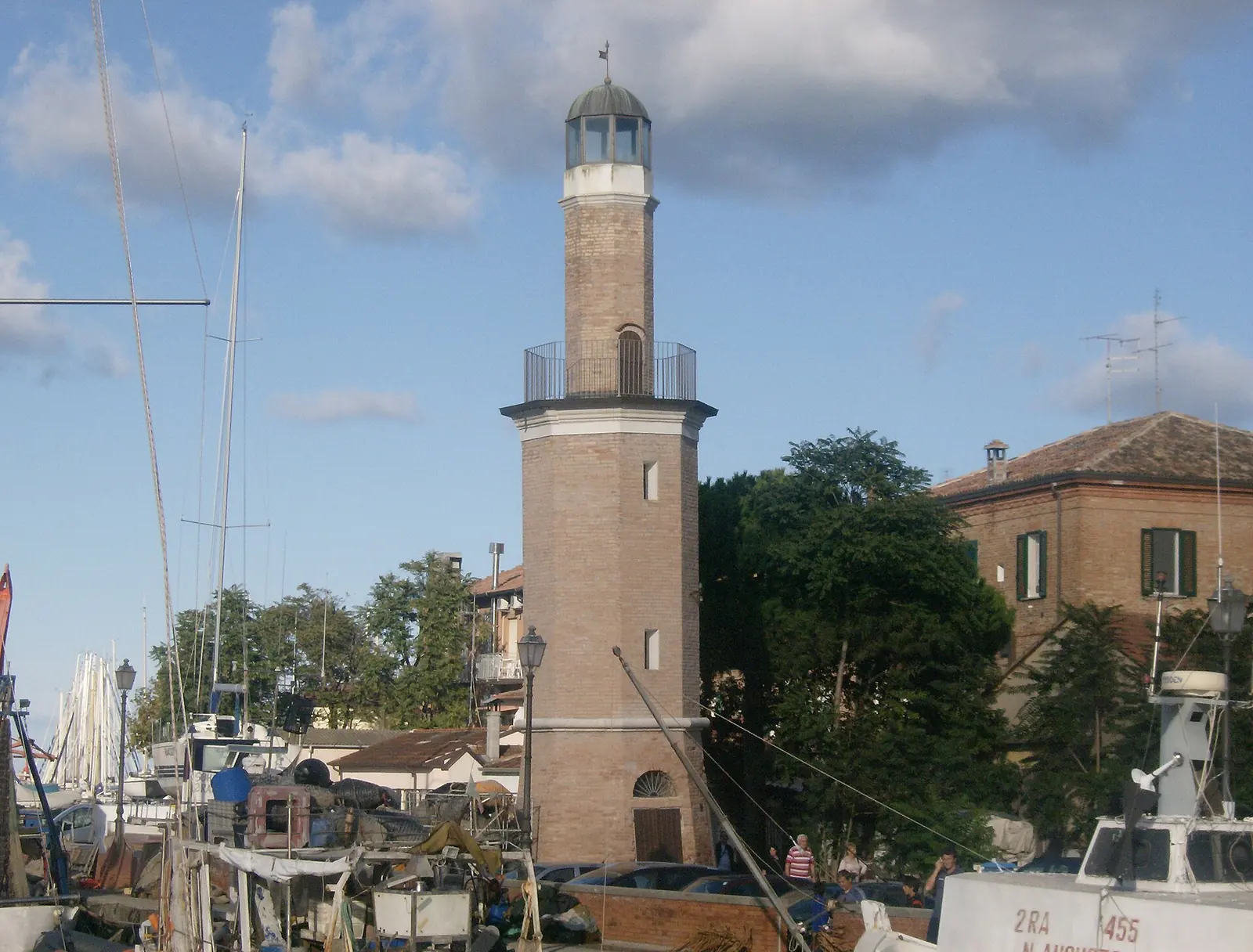 The brick lighthouse at Cervia canal harbour, with fishing boats moored at its foot
