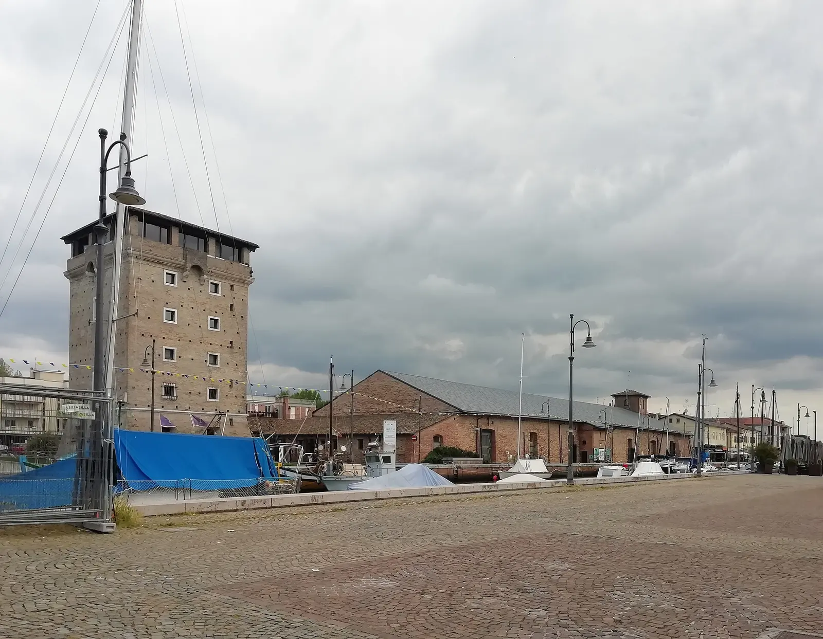 La Torre San Michele à gauche et le Magazzino Torre à droite sur le port-canal de Cervia, par temps nuageux