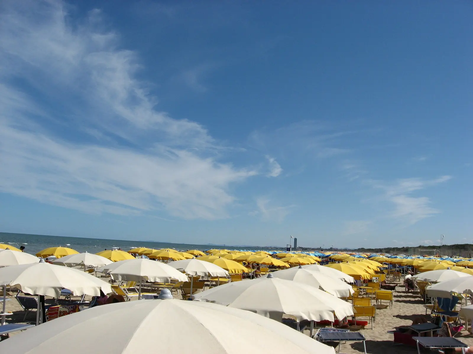 White and yellow parasols on Cervia beach, with the sea in the background