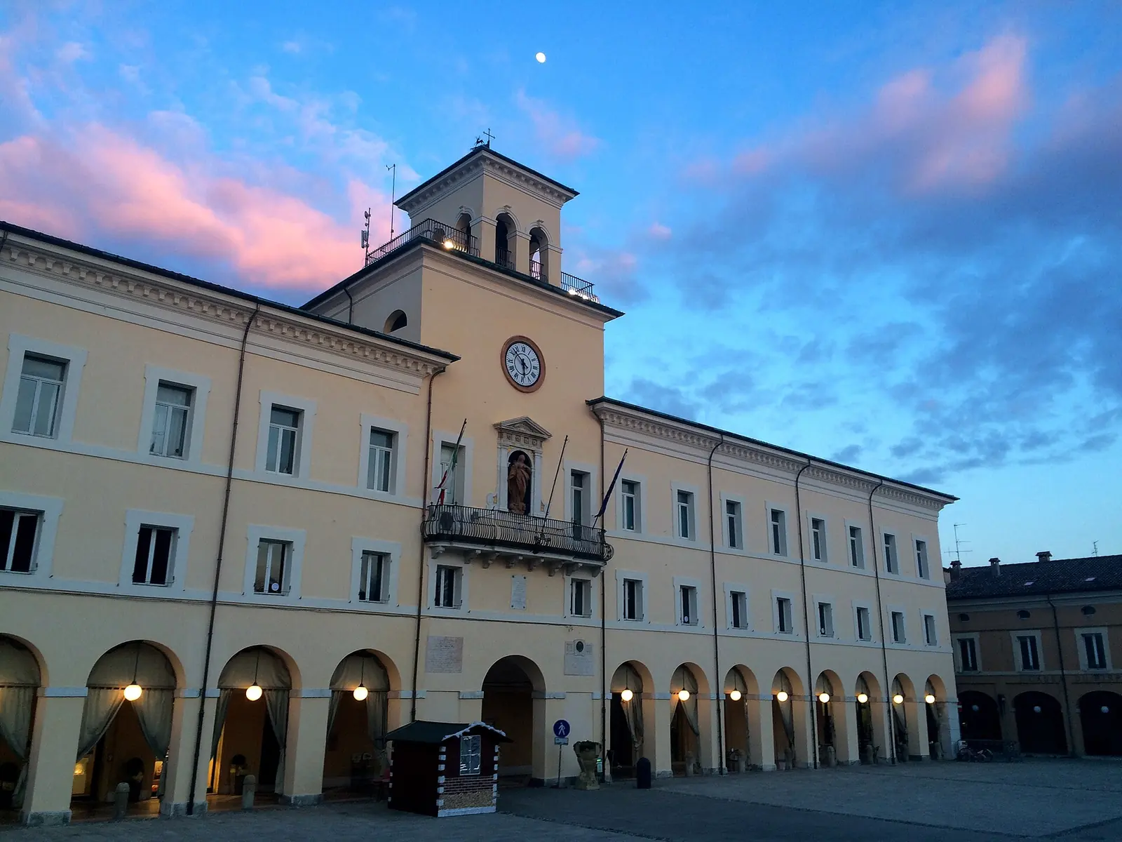 Palazzo comunale in Cervia with its arcade, clock tower and the pink sky at dusk