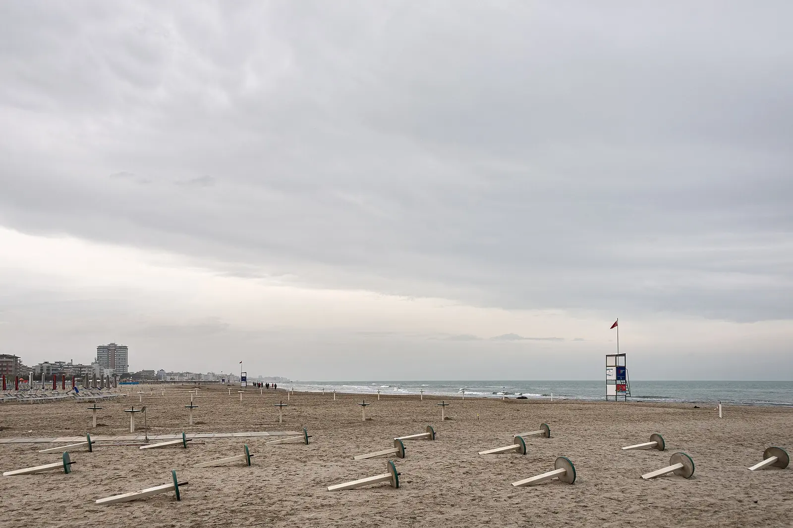 La spiaggia di Cervia prima della stagione, con i basamenti degli ombrelloni sulla sabbia e una torretta di salvataggio