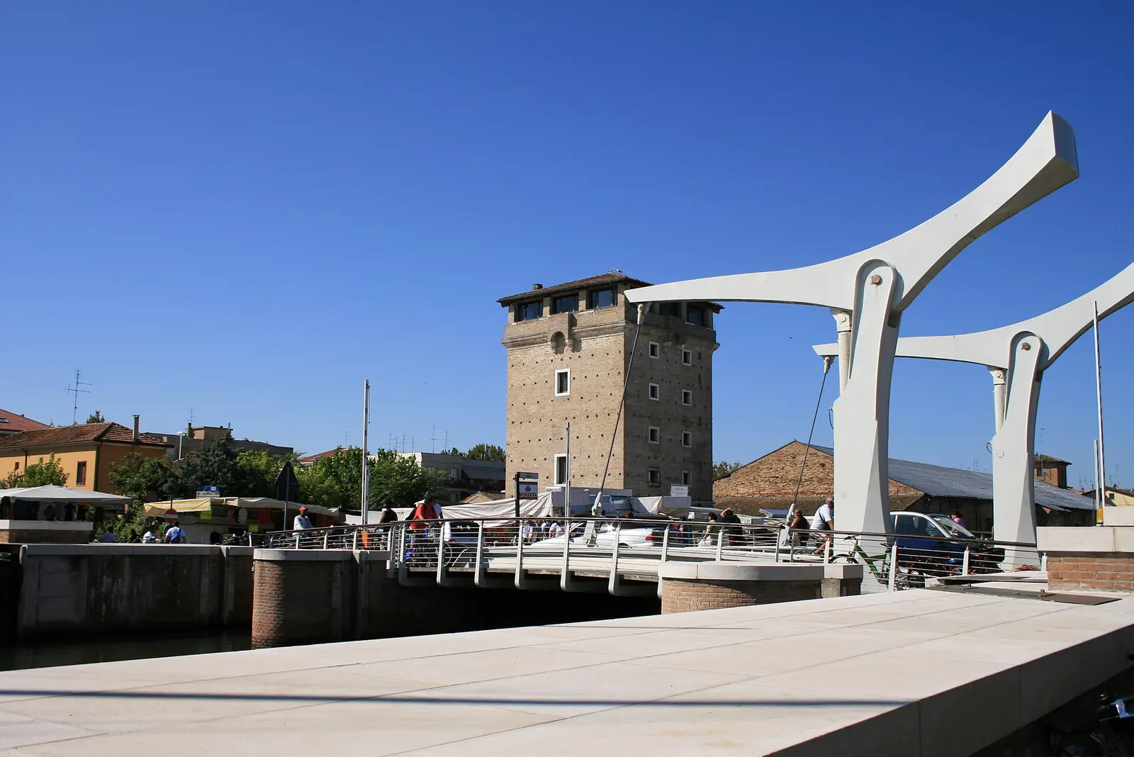 La Torre San Michele di Cervia accanto al ponte mobile bianco sul porto canale, con tende bianche sulla banchina