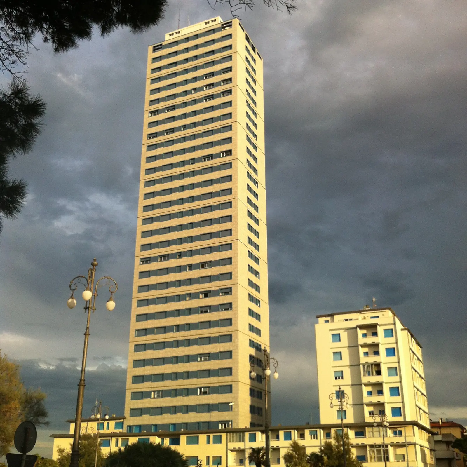 Der Grattacielo von Cesenatico von unten unter dunklem Himmel mit Straßenlaternen im Vordergrund