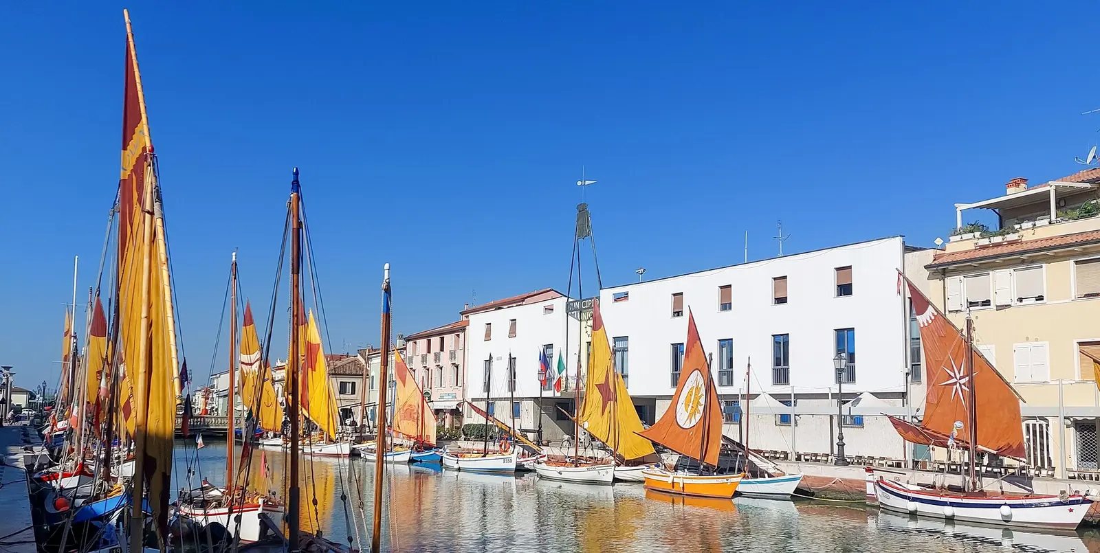 Die bunten Segel der historischen Boote des Museo della Marineria am Kanal vor einem weißen Gebäude