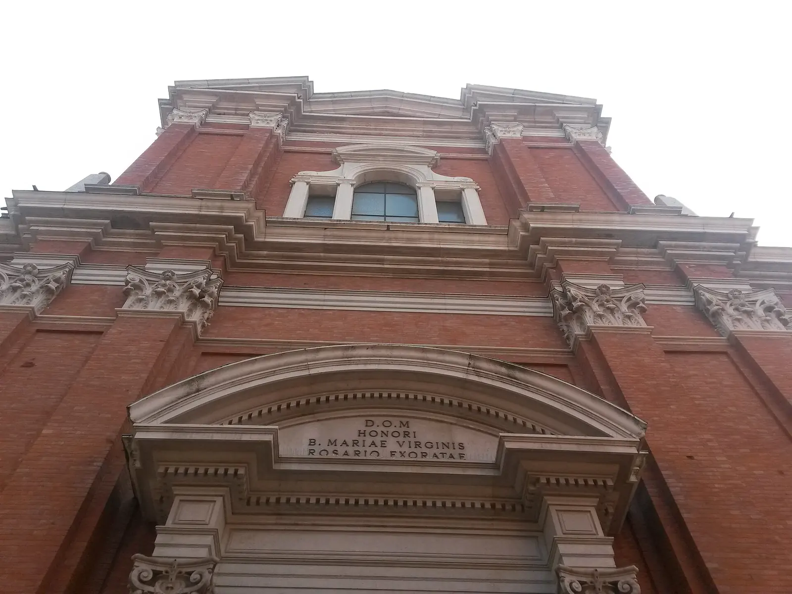 Die Fassade der Chiesa di Santa Maria dei Servi in Rimini aus Backstein und weißem Stein von unten gesehen