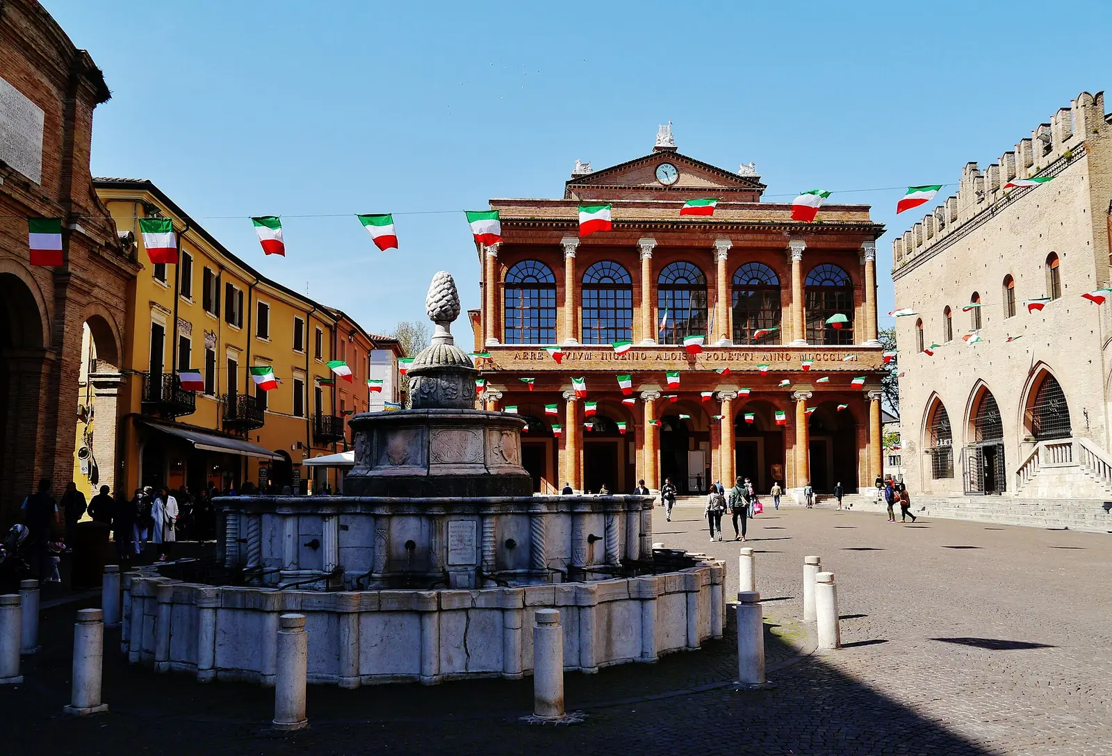 La Fontana della Pigna in piazza Cavour a Rimini, con il Teatro Galli sullo sfondo e le bandierine tricolori