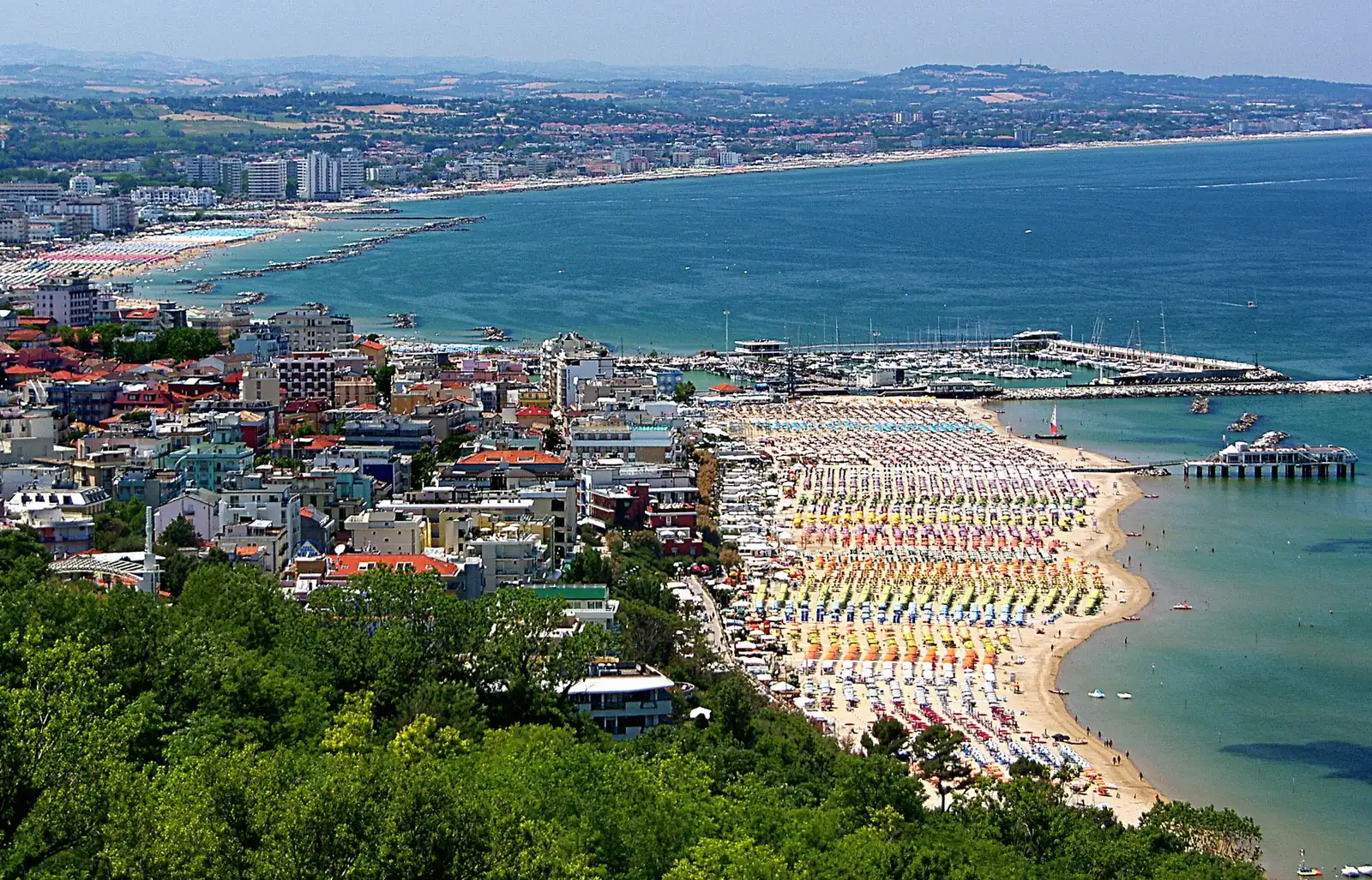 Gabicce Mare vista dall'alto di Gabicce Monte, con la spiaggia, il porto, un pontile e la costa fino a Cattolica sullo sfondo