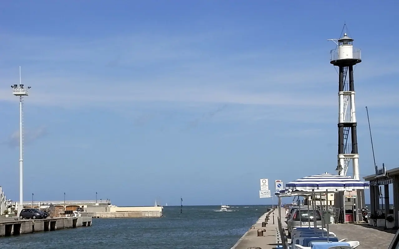 L'imboccatura del porto canale sul Tavollo, con il molo, il faro a traliccio bianco e nero e il mare aperto sullo sfondo