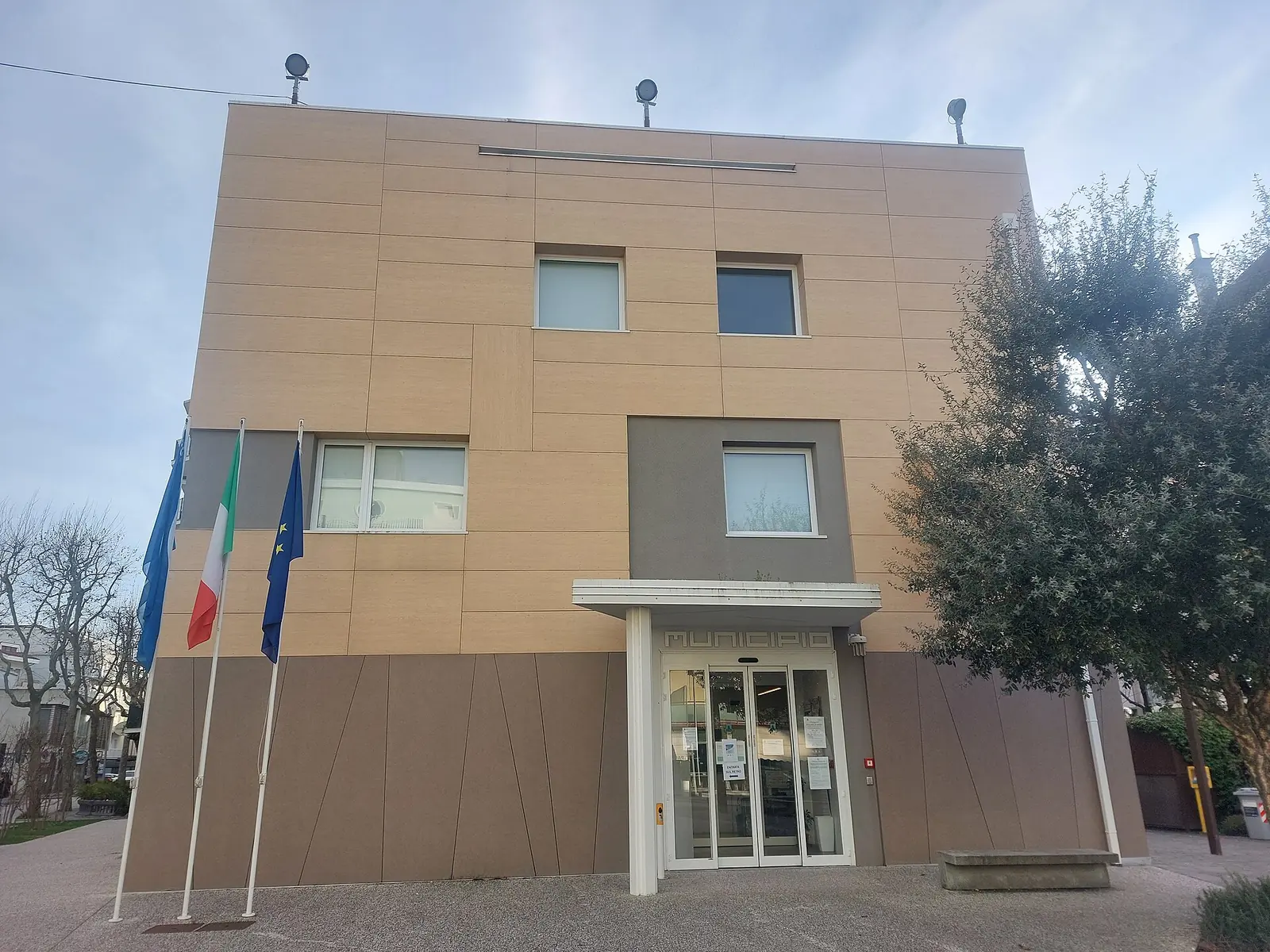 La facciata del municipio di Gabicce Mare, con l'ingresso a vetri sotto una pensilina e le bandiere sui pennoni