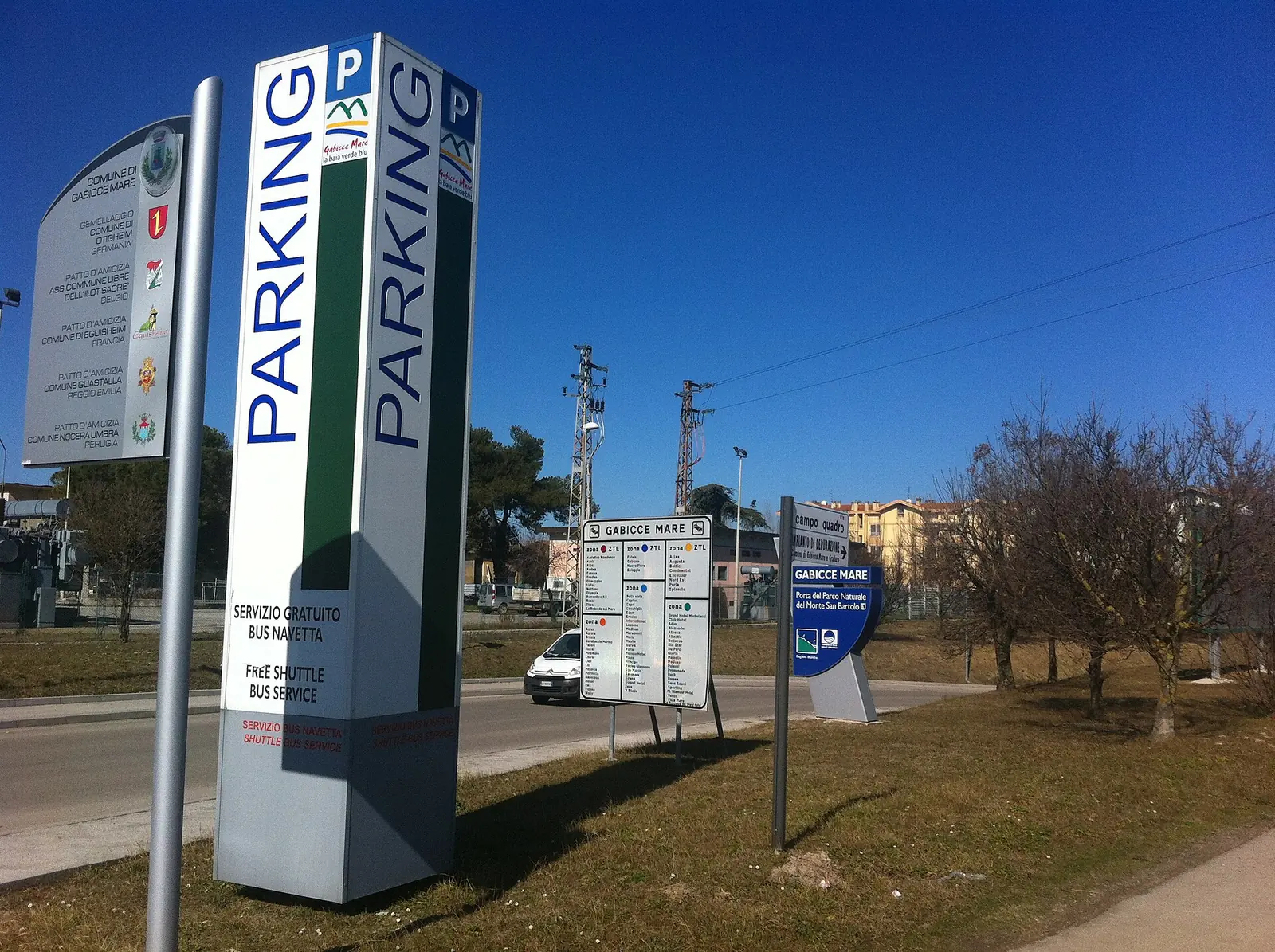 Das Parkplatzschild mit kostenlosem Busshuttle am Ortseingang von Gabicce Mare mit der Straße im Hintergrund