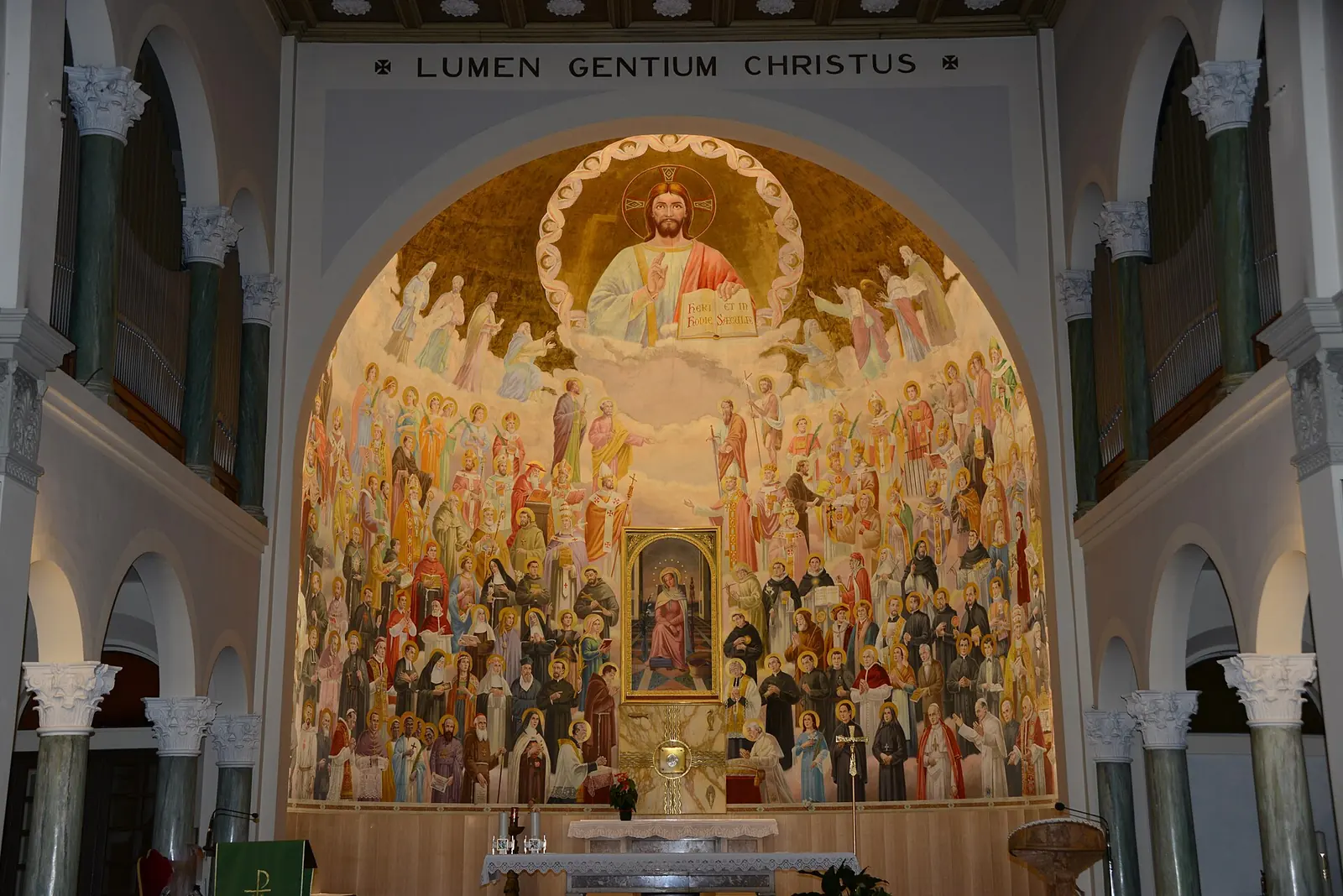 L'abside affrescata della chiesa Mater Admirabilis: il Cristo in alto, una folla di santi e la scritta Lumen Gentium Christus