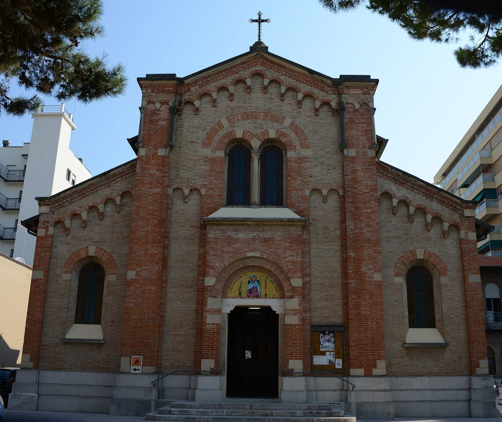 La facciata in mattoni rossi e chiari della chiesa Mater Admirabilis, con il portale ad arco e il mosaico nella lunetta