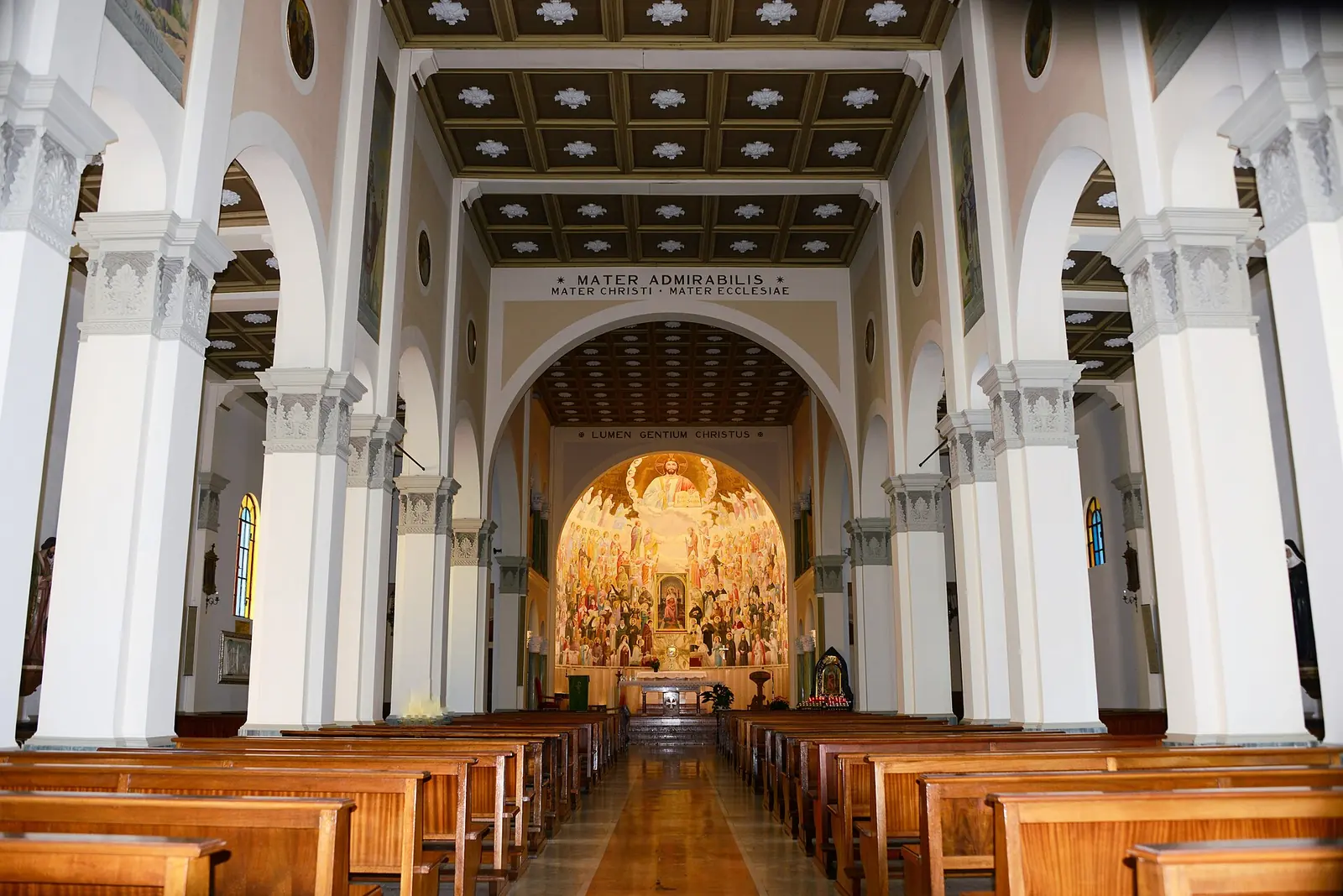 La navata della chiesa Mater Admirabilis a Riccione, con colonne bianche, soffitto a cassettoni e l'abside affrescata