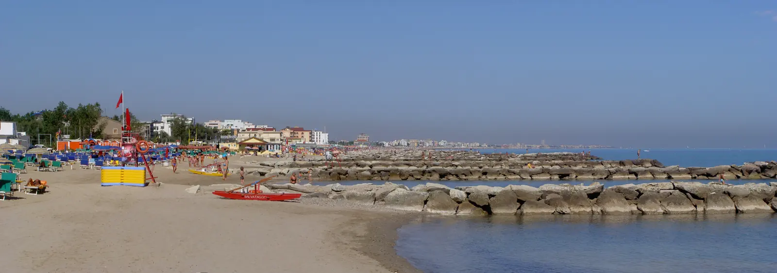 Der Sandstrand von Misano Adriatico mit parallel zum Ufer verlaufenden Wellenbrechern und ruhigem Meer