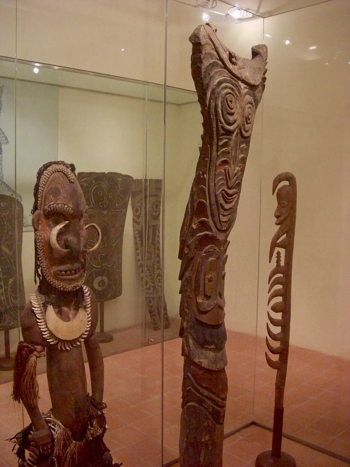 Geschnitzte Holzskulpturen mit Muscheln und Zähnen sowie ein Hakenstab in einer Vitrine des Museo degli Sguardi