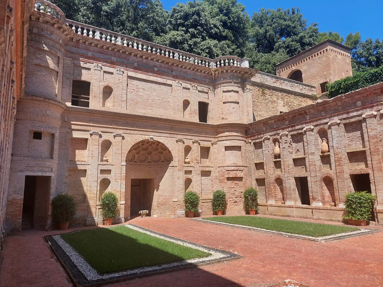 Der Hof der Villa Imperiale in Pesaro mit Backsteinwänden, Amphorennischen und Hecken in Kübeln