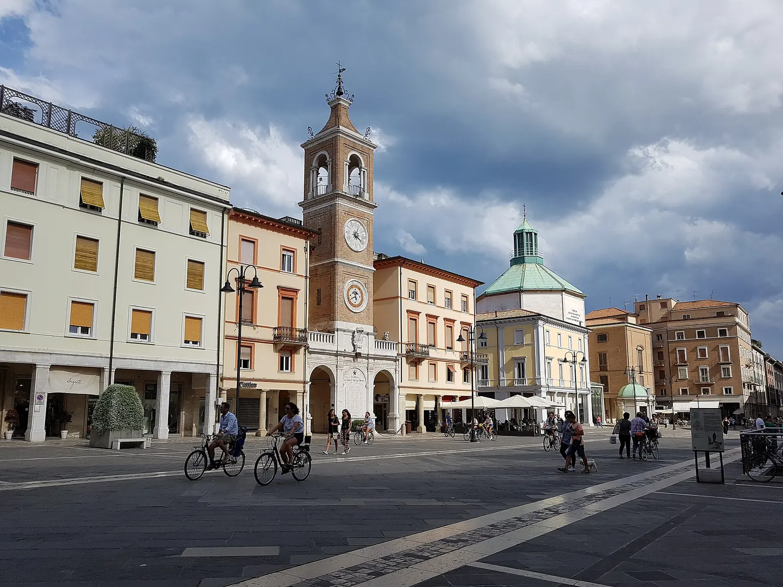 Piazza Tre Martiri a Rimini con la Torre dell'Orologio, i palazzi porticati, la chiesa dei Paolotti con la cupola verde e il tempietto di Sant'Antonio