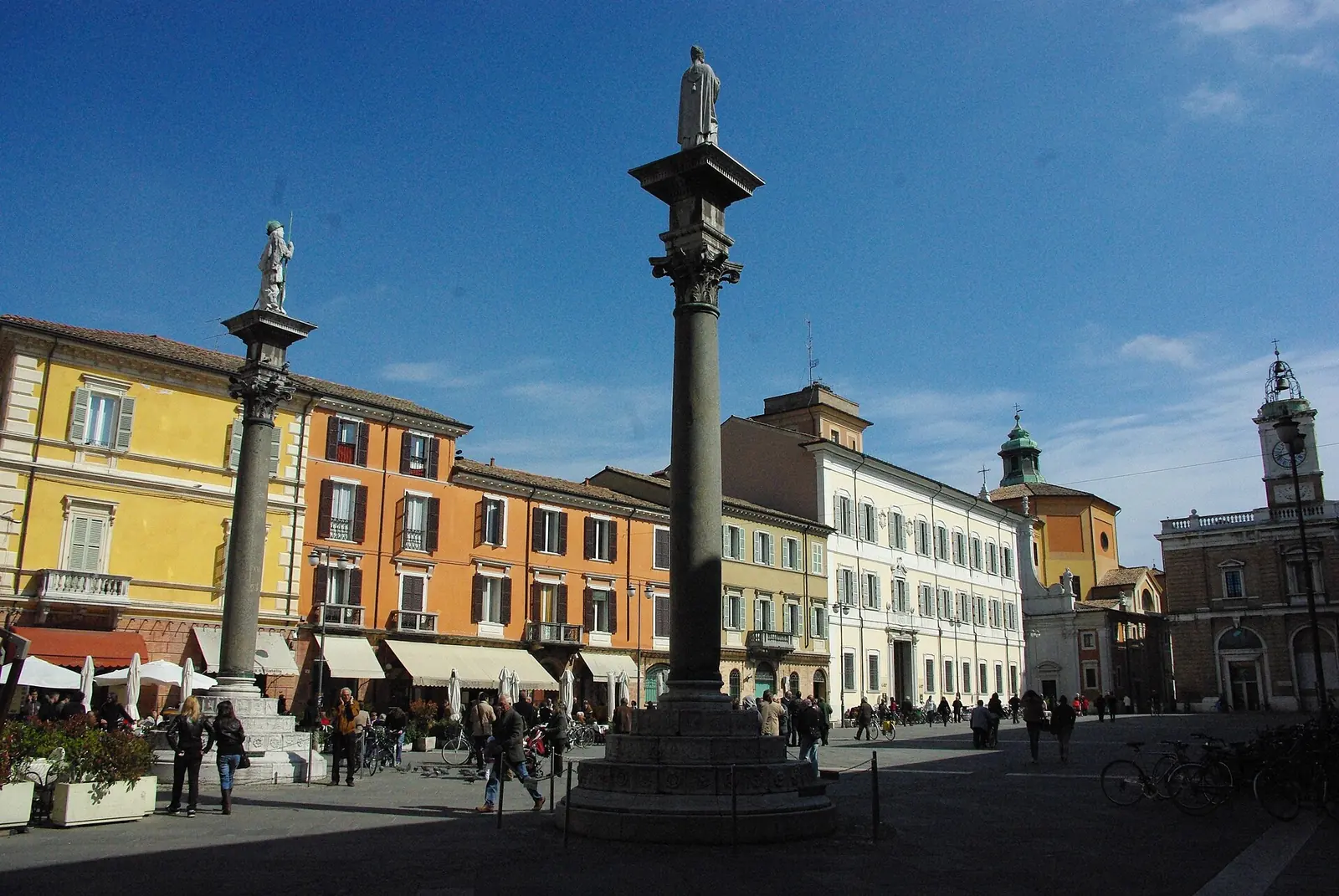 Piazza del Popolo a Ravenna, con le due colonne con statue, i palazzi colorati e i tavolini all'aperto