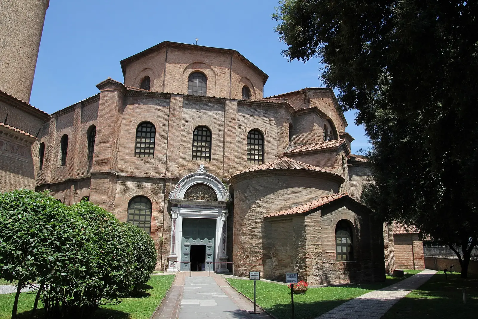 L'ingresso della Basilica di San Vitale a Ravenna, con la massa ottagonale in mattoni e un vialetto verso il portale