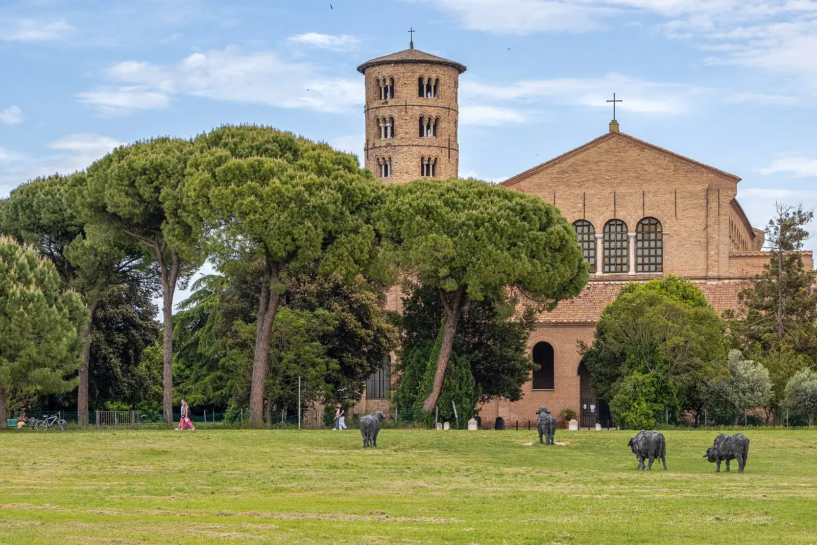 Basilica di Sant'Apollinare in Classe in Ravenna, with its cylindrical bell tower, among pines and cattle sculptures on the lawn