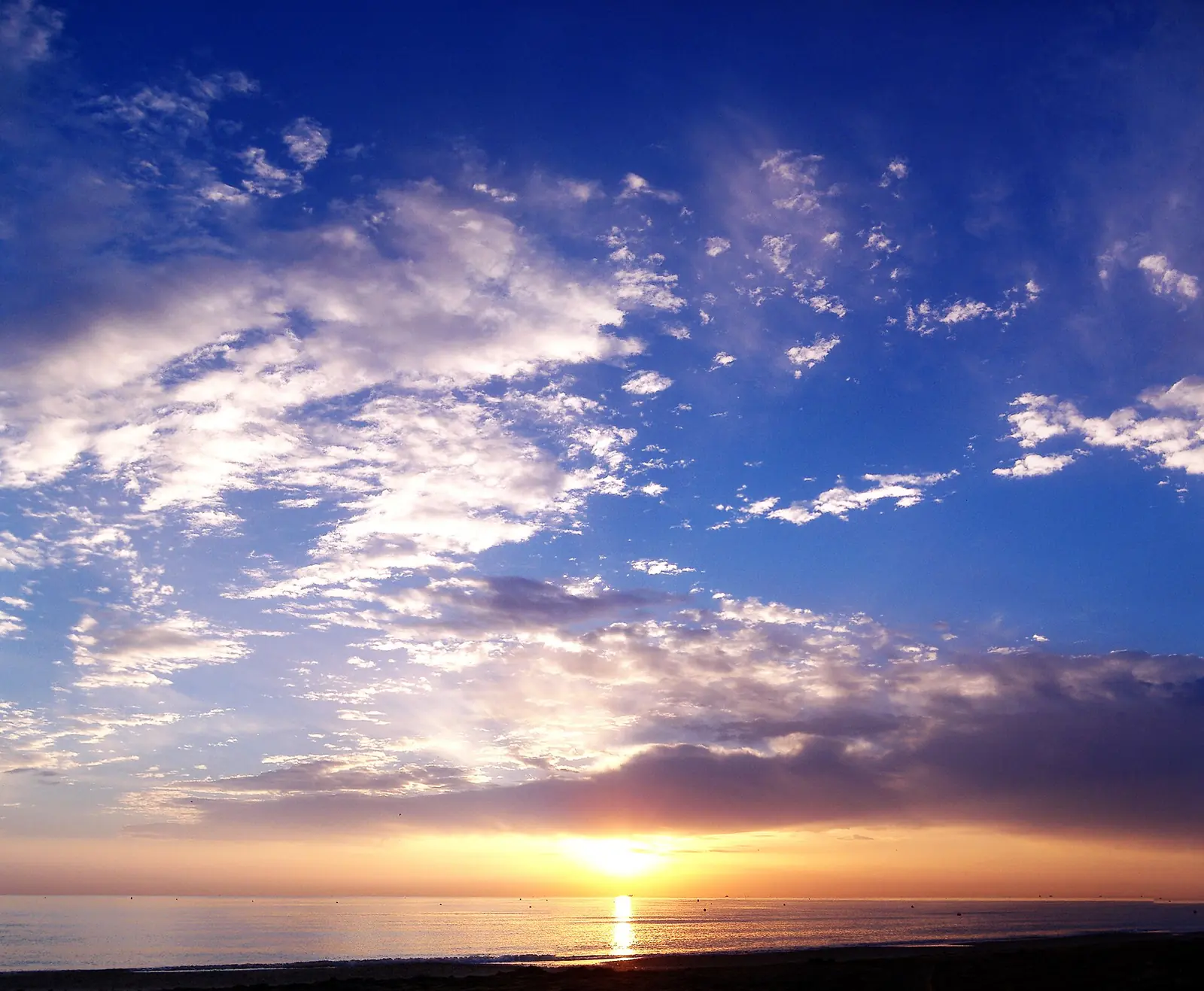Dawn over the sea at Riccione, with clouds lit by the sun rising above the horizon