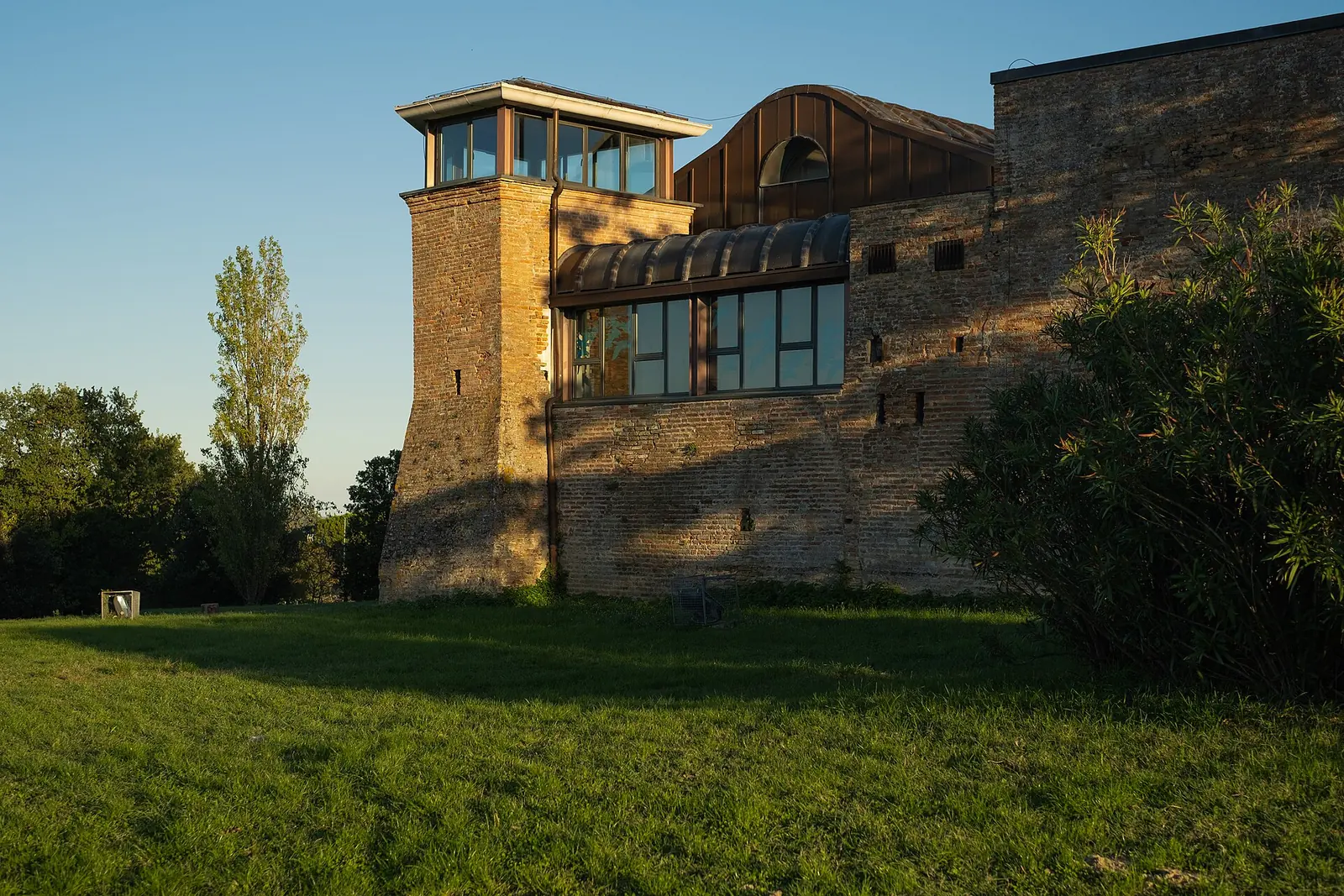 Il Castello degli Agolanti a Riccione, con la torre in mattoni, il corpo vetrato e il prato davanti