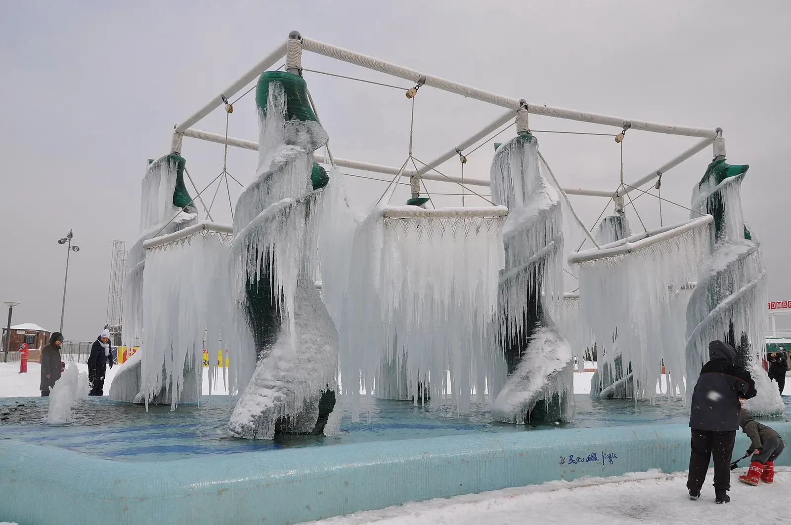 La fontaine du Piazzale Roma à Riccione couverte de glace après une chute de neige, avec deux personnes en arrière-plan