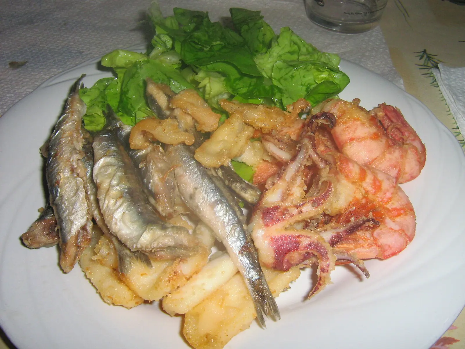Piatto di fritto misto di pesce con alici, calamari e gamberi su un letto di insalata
