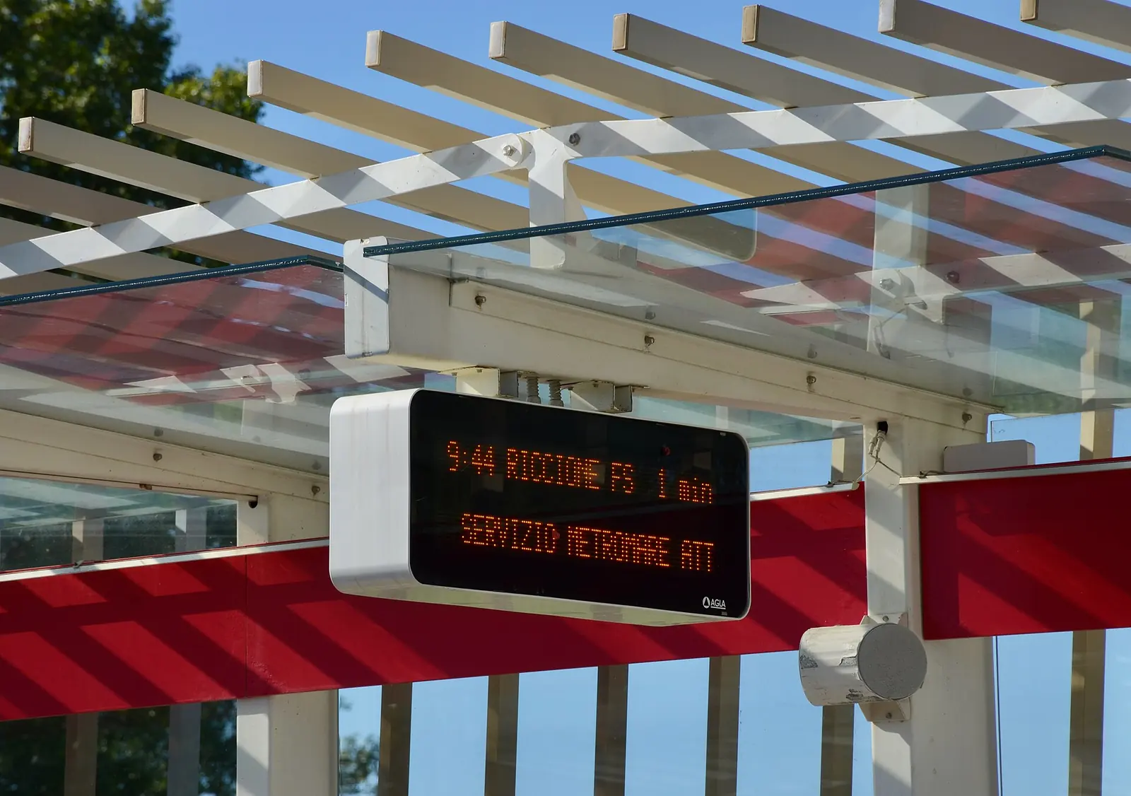 An electronic board at a Metromare stop, with the shelter and upcoming arrival information