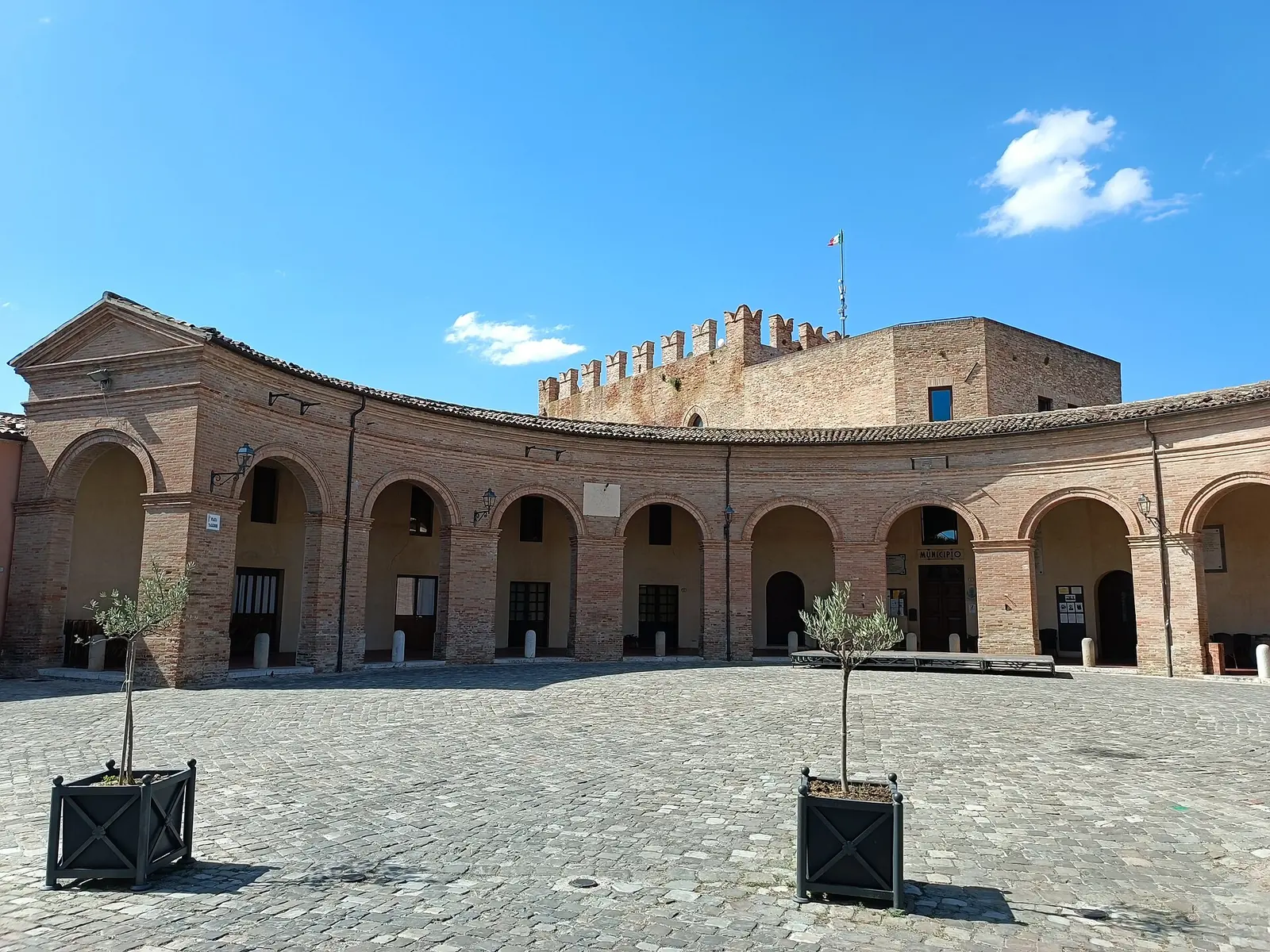 La piazza a semicerchio di Mondaino con il loggiato in mattoni e la rocca merlata sullo sfondo