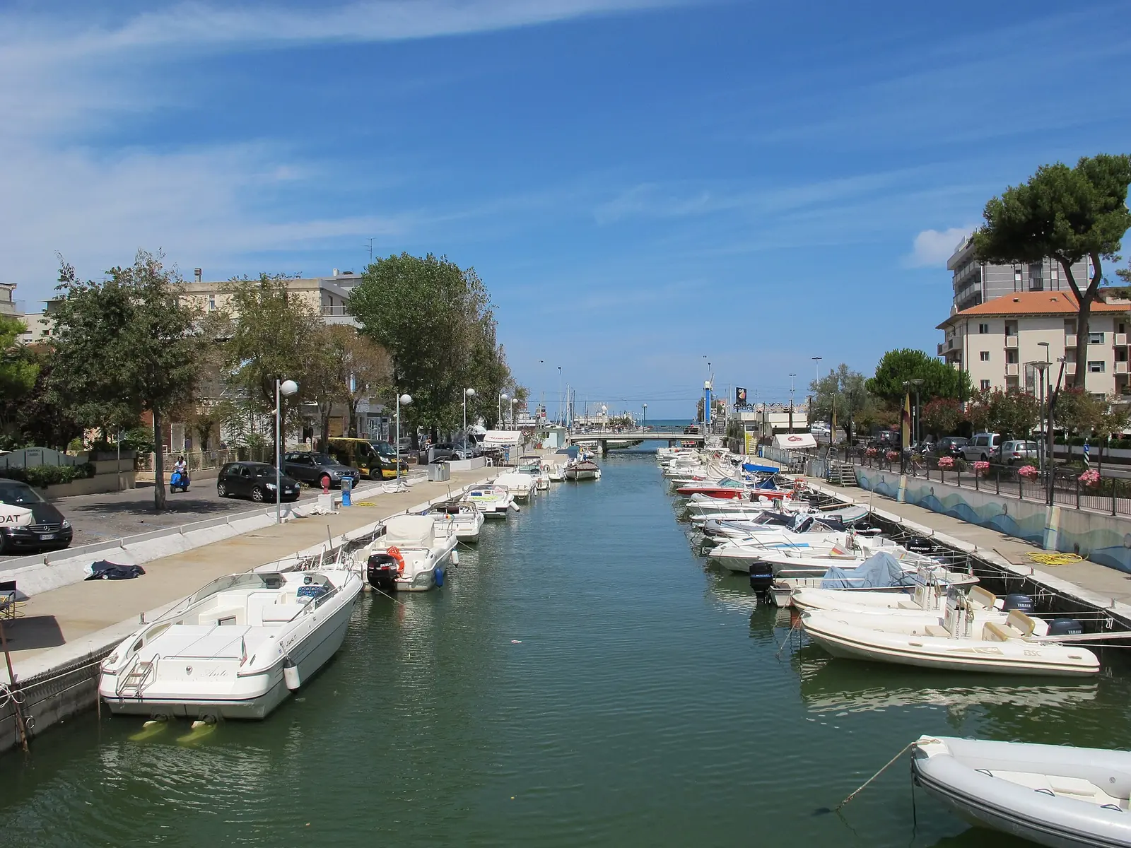 Il porto canale di Riccione con le barche ormeggiate lungo le banchine e il ponte verso il mare in fondo